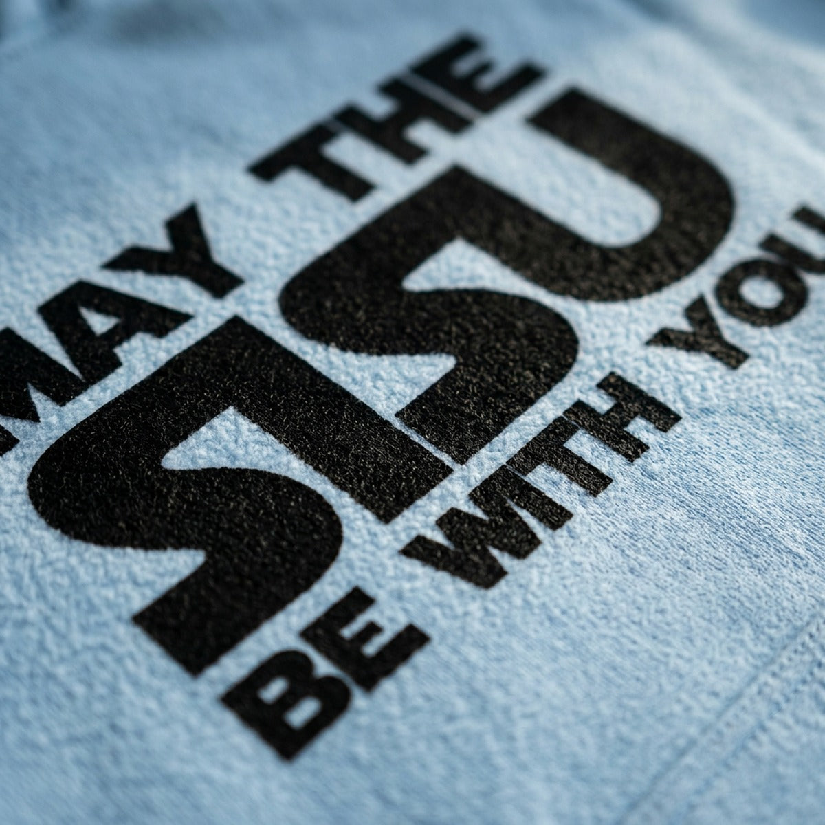 Close-up macro of light blue May the Sisu hoodie print, Very Finnish Problems