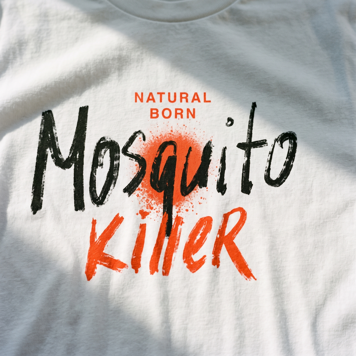 Close-up of the Natural Born Mosquito Killer print on white t-shirt fabric, Very Finnish Problems
