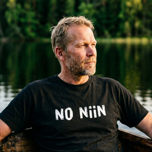 Man in a rowing boat on a Finnish lake wearing the black No niin t-shirt, Very Finnish Problems