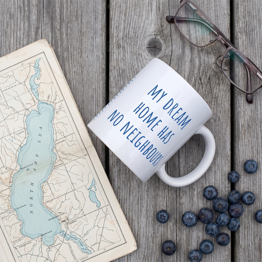 My Dream Home Has No Neighbours mug on a jetty with a lake map, reading glasses and blueberries, Very Finnish Problems
