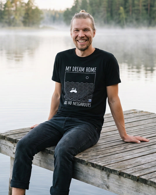 No Neighbours t-shirt in black, worn by Joonas sitting on the end of a lake jetty with his feet in the water, Very Finnish Problems