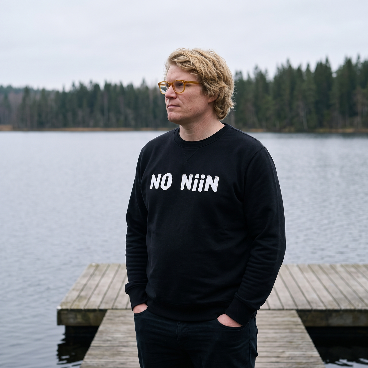 No niin eco-friendly Finnish language sweatshirt in black, worn by Tuomas on a Finnish lake jetty, Very Finnish Problems