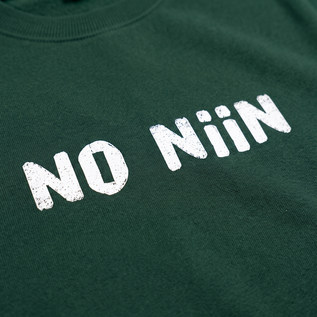 Close-up of the No niin print on bottle green organic sweatshirt fabric, Very Finnish Problems