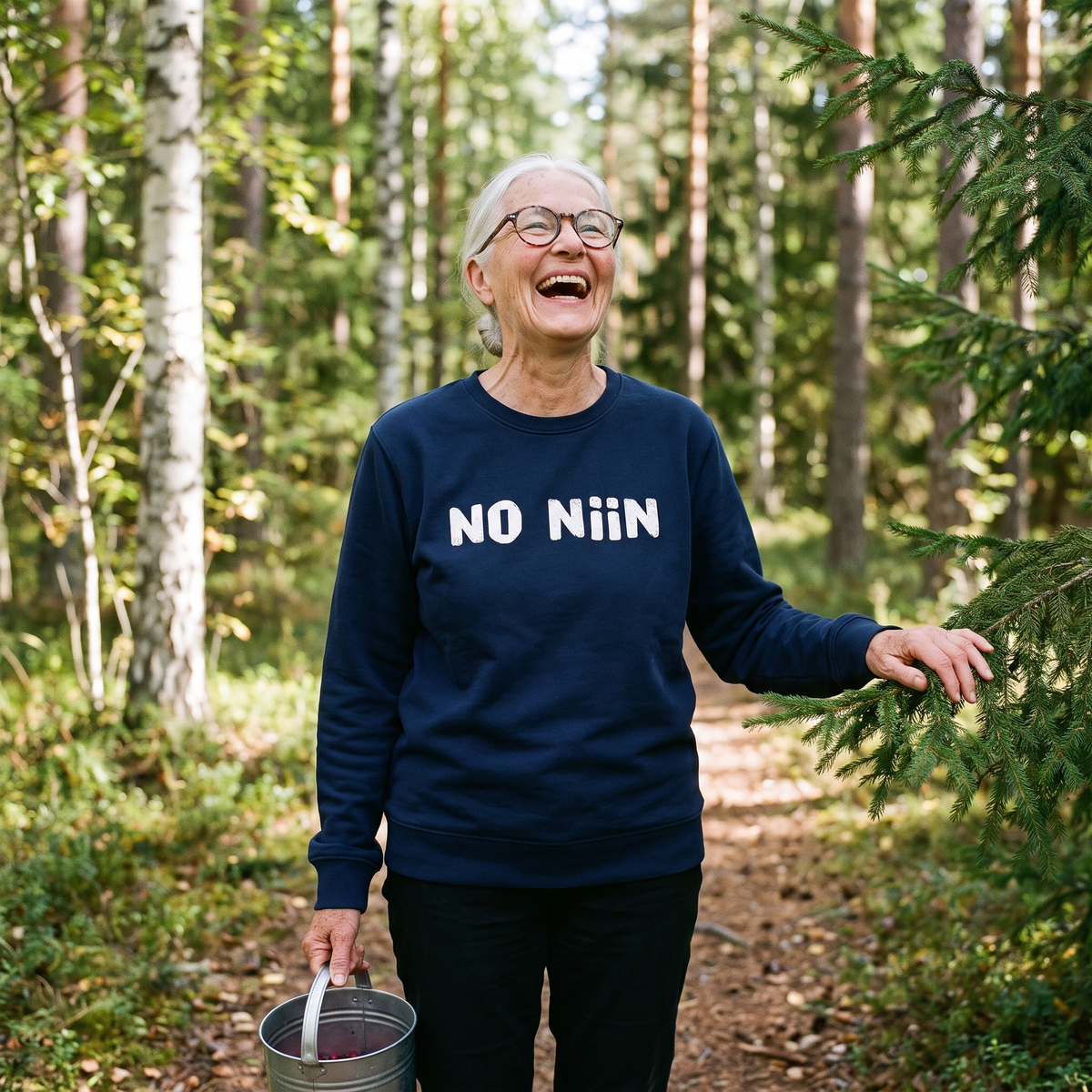 No niin eco-friendly Finnish language sweatshirt in French navy, worn by Raija laughing on a Finnish forest path, Very Finnish Problems
