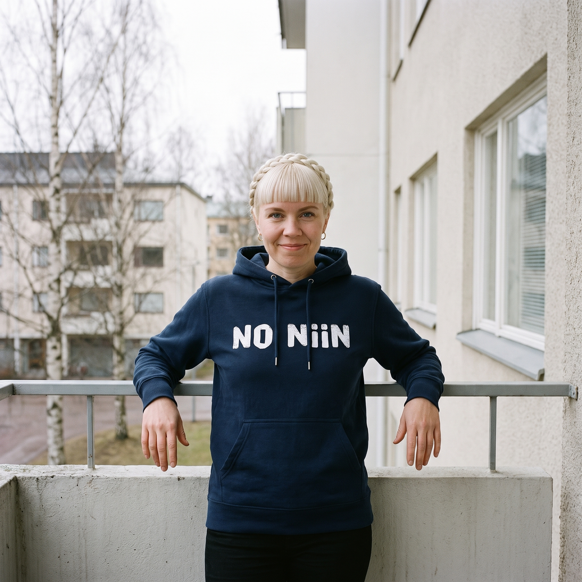 No niin essential eco Finnish language hoodie in French navy, worn by Venla on a Finnish balcony, Very Finnish Problems