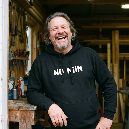 No niin hoodie in black, worn by Jojelli laughing in a Finnish workshop doorway, Very Finnish Problems