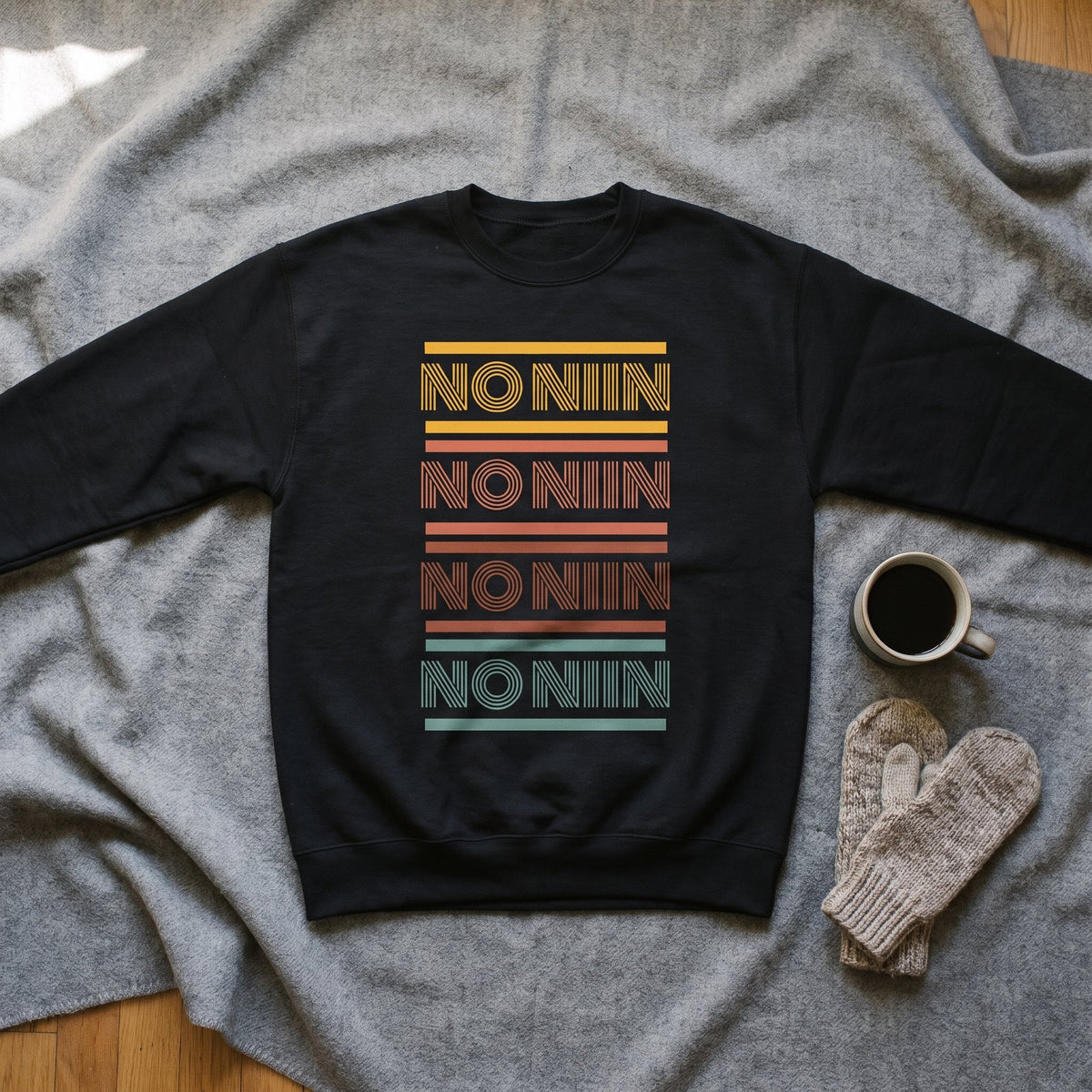 The four-row No niin retro print on a black crew neck sweatshirt laid flat on a grey wool blanket, Very Finnish Problems