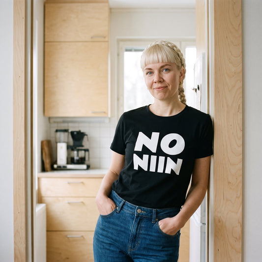 Venla wearing the black No niin stacked t-shirt in a kitchen doorway, Very Finnish Problems