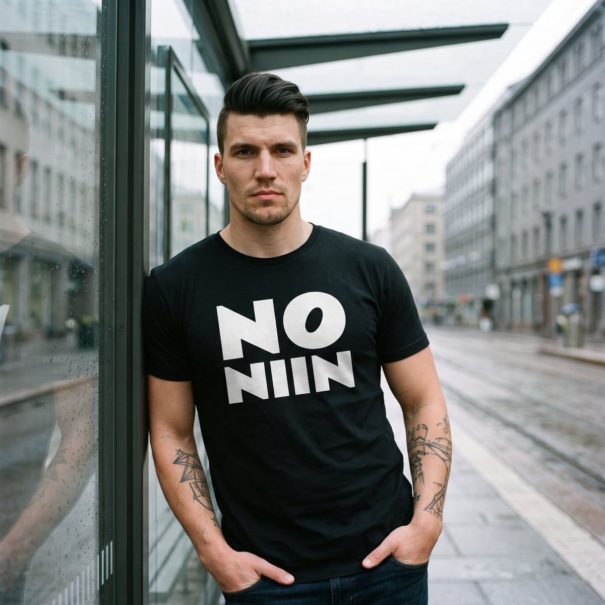 Eetu wearing the black No niin stacked t-shirt at a Helsinki tram stop, Very Finnish Problems