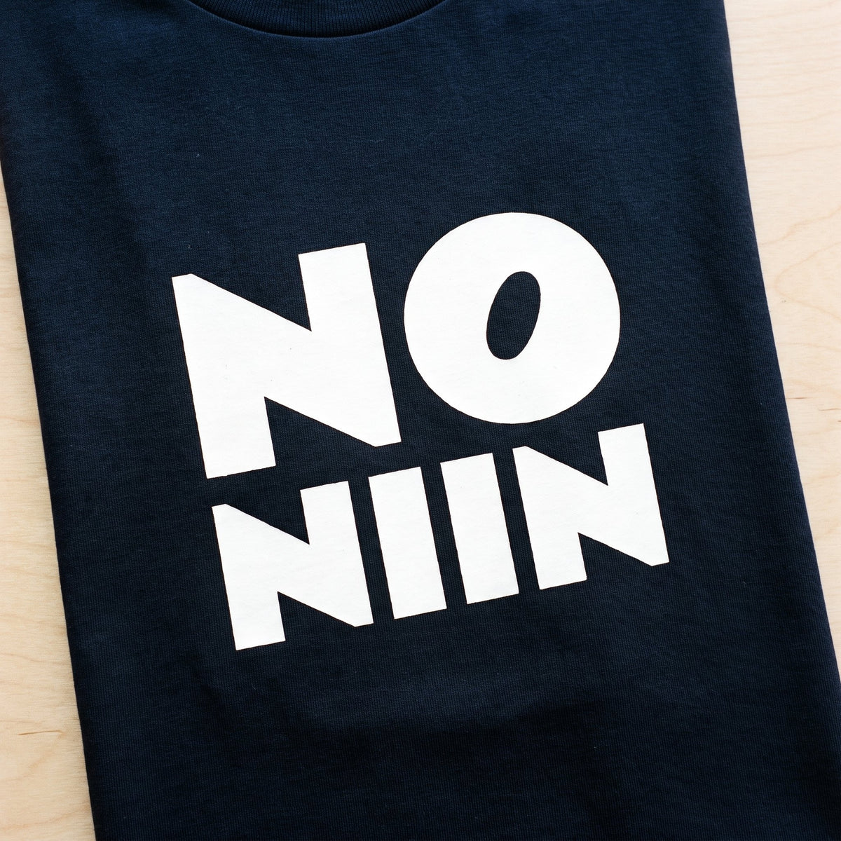Close-up of the No niin stacked print in white on a navy t-shirt, Very Finnish Problems