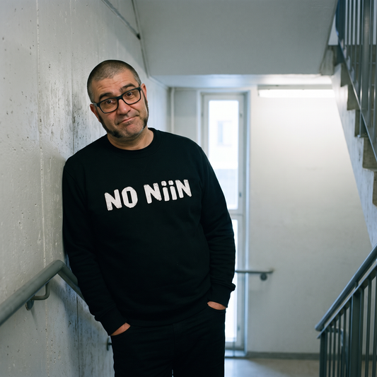 No niin Finnish language sweatshirt in black, worn by Jaska in a Finnish car park stairwell, Very Finnish Problems