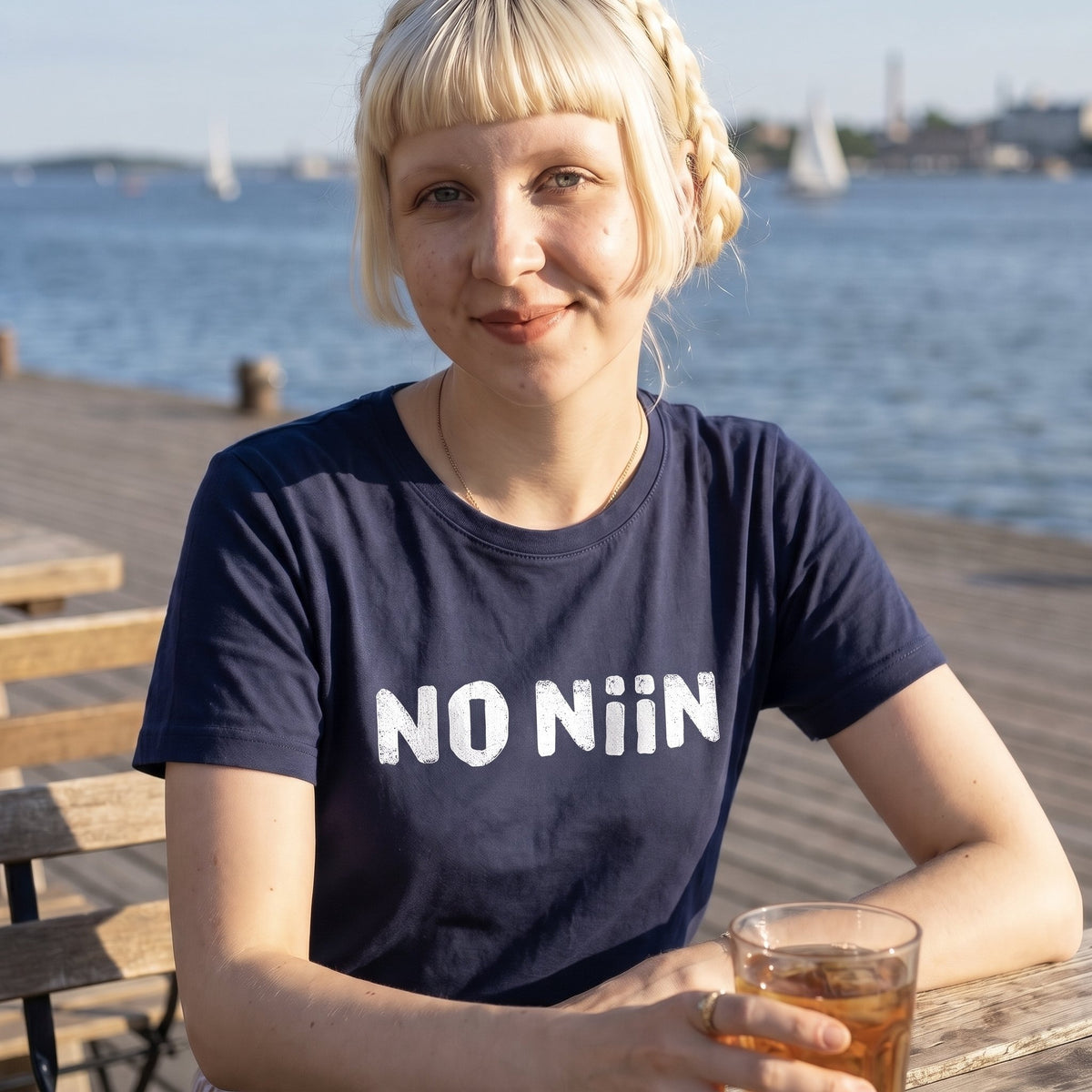 Woman wearing the navy No niin t-shirt on a Helsinki harbour pier, Very Finnish Problems
