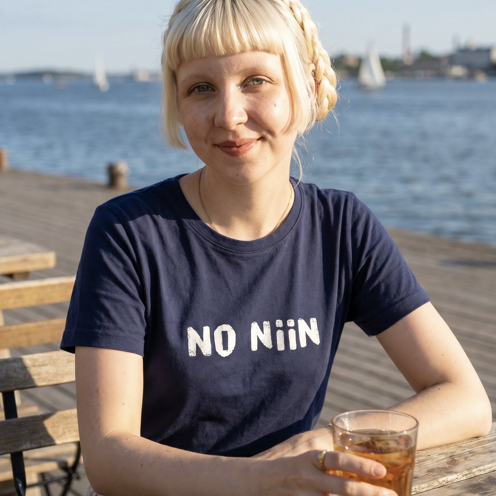 Woman wearing the No niin Finnish language t-shirt in navy by the water in Helsinki, Very Finnish Problems