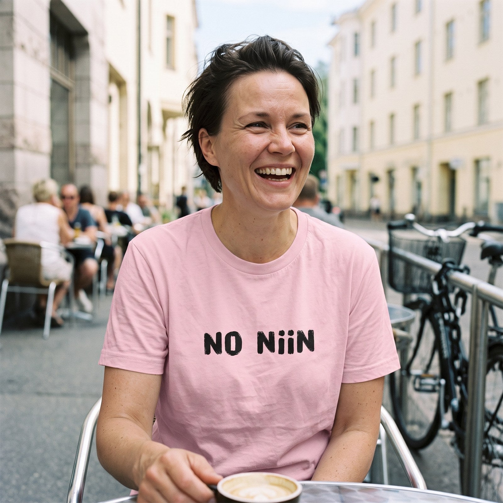 Woman wearing the pink No niin Finnish language t-shirt on a Helsinki cafe terrace, Very Finnish Problems