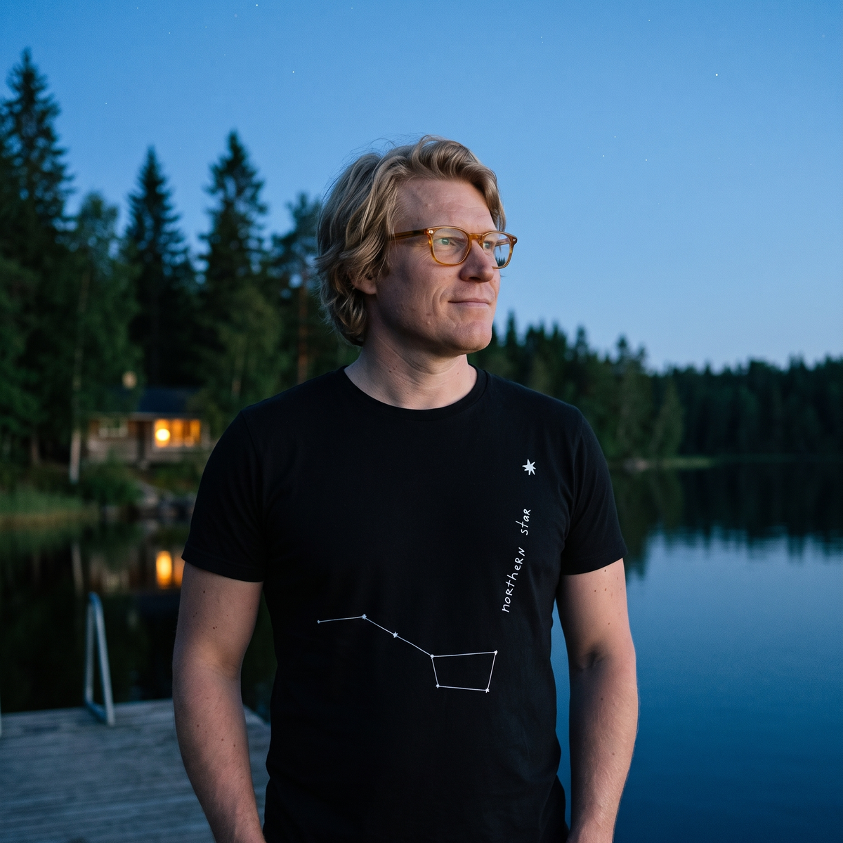 Northern Star 2 organic t-shirt in black, worn by Tuomas on a lake jetty at dusk, Very Finnish Problems