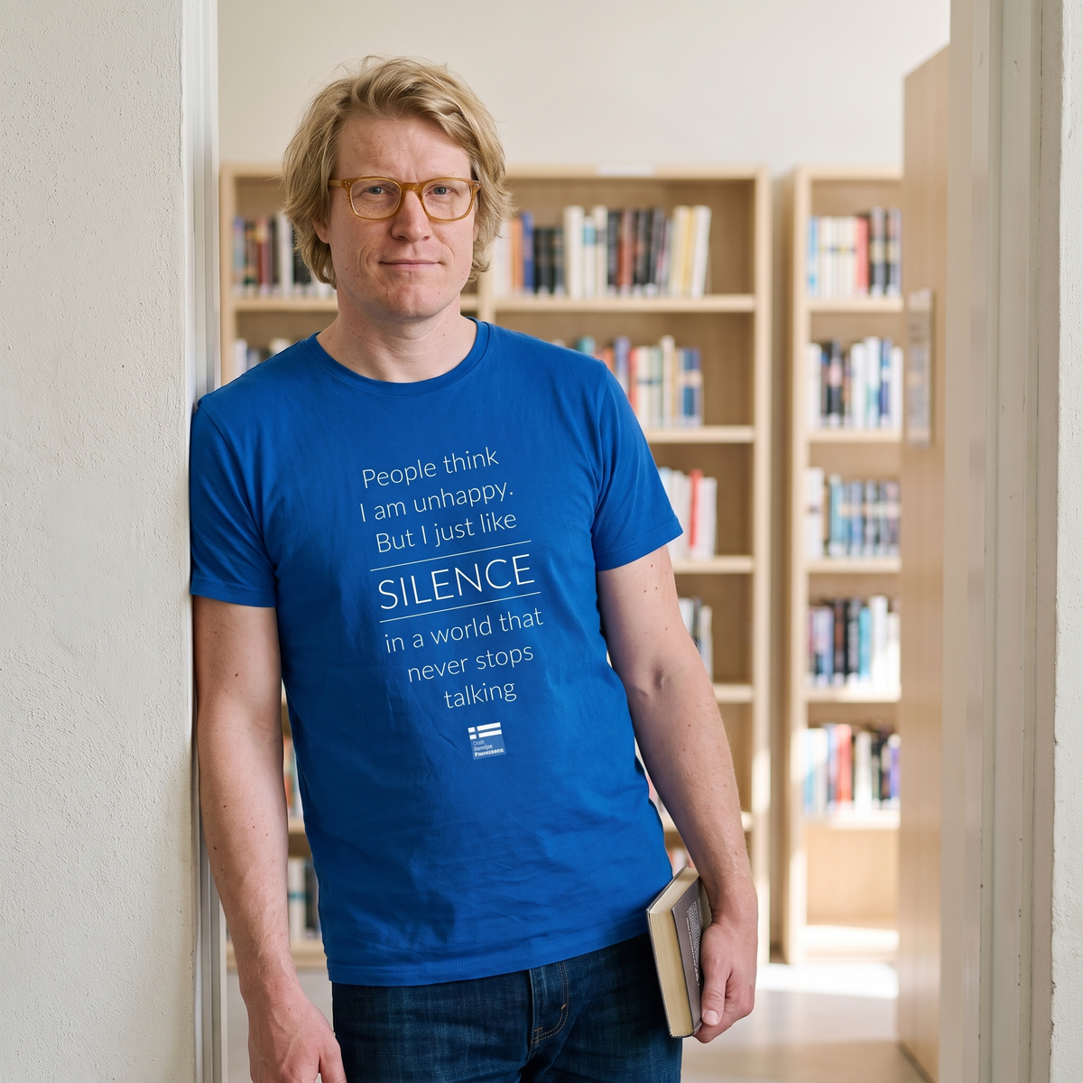 Not Unhappy Just Silent t-shirt in blue, worn by Tuomas in a quiet library doorway, Very Finnish Problems