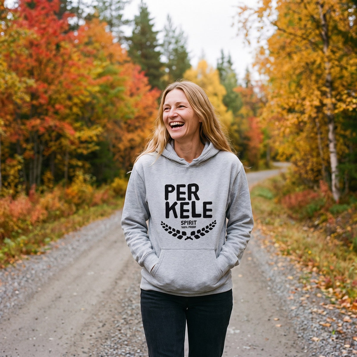 Perkele 100% Proof hoodie in sport grey, worn by Elina on a Lapland forest road, Very Finnish Problems