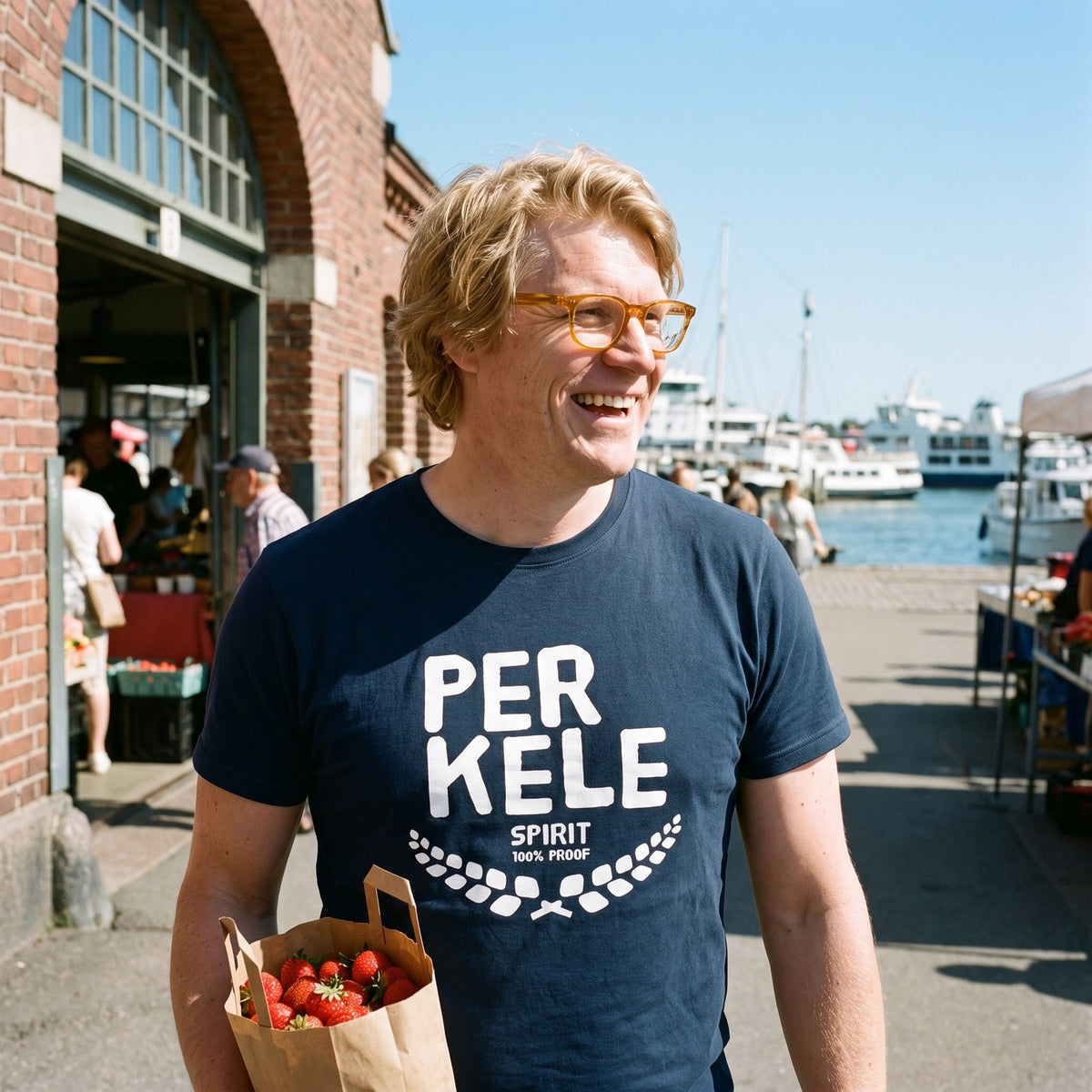Perkele 100% Proof organic t-shirt in french navy, worn by Tuomas outside a Helsinki market hall, Very Finnish Problems