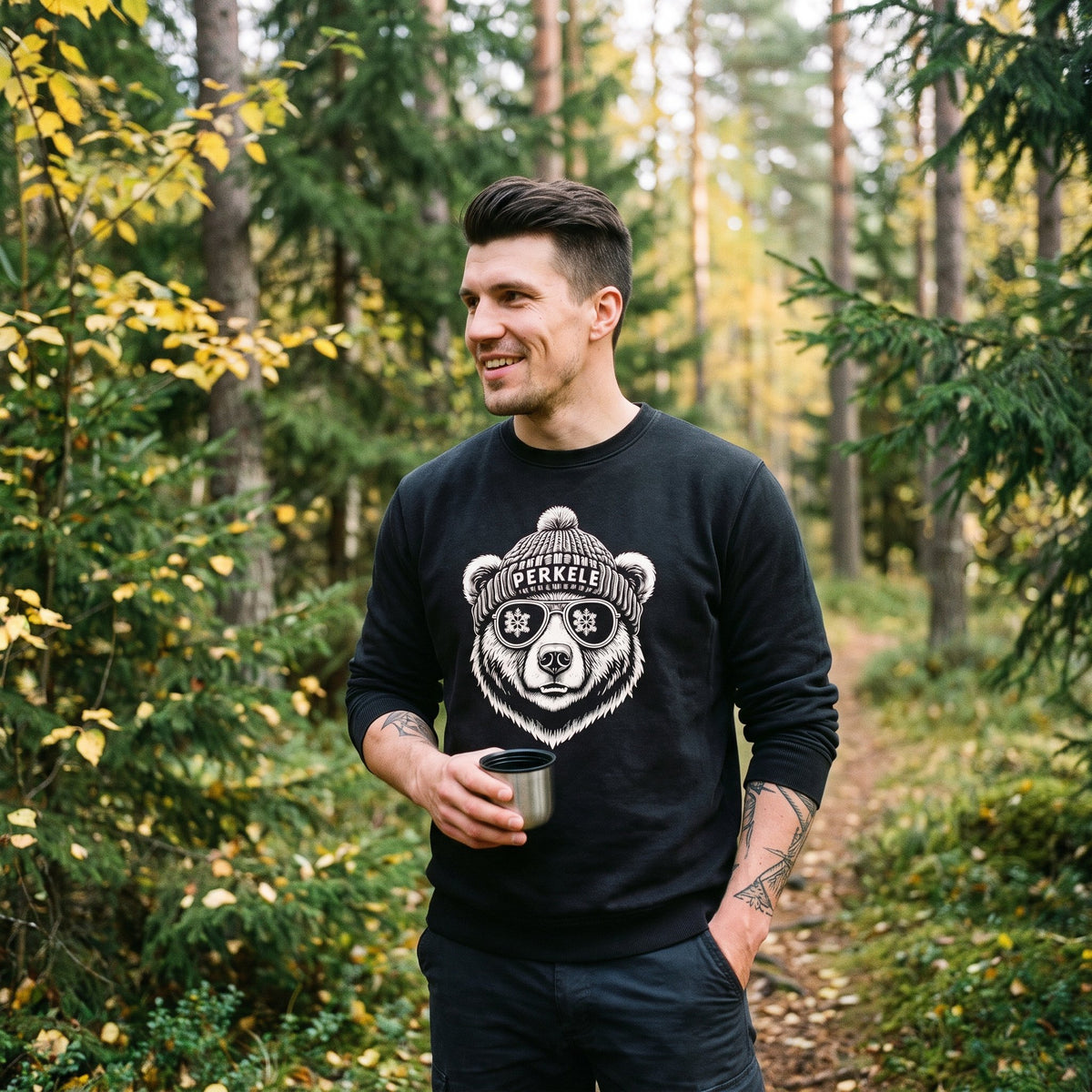 Perkele Bear sweatshirt in black, worn by Eetu with a thermos cup on an autumn forest trail, Very Finnish Problems