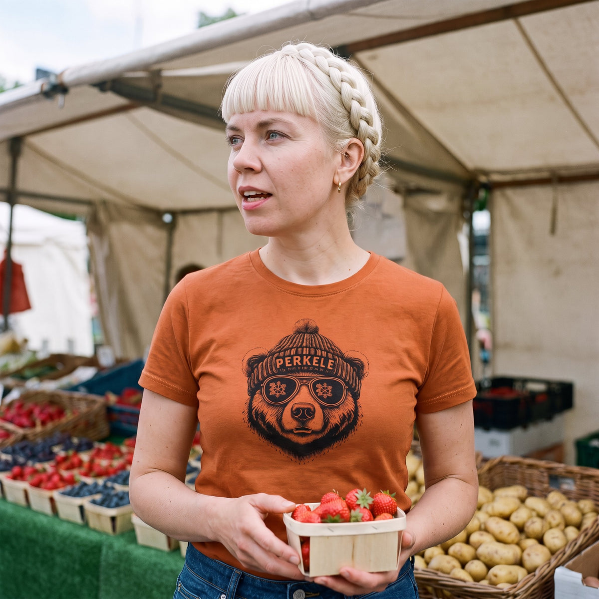 Perkele Bear t-shirt in burnt orange, worn by Venla buying strawberries at a summer market, Very Finnish Problems