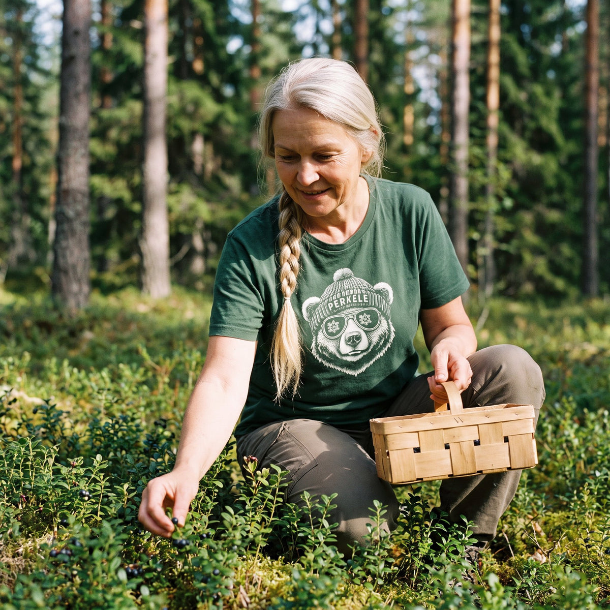 Perkele Bear t-shirt in forest green, worn by Anneli picking bilberries in a spruce forest, Very Finnish Problems