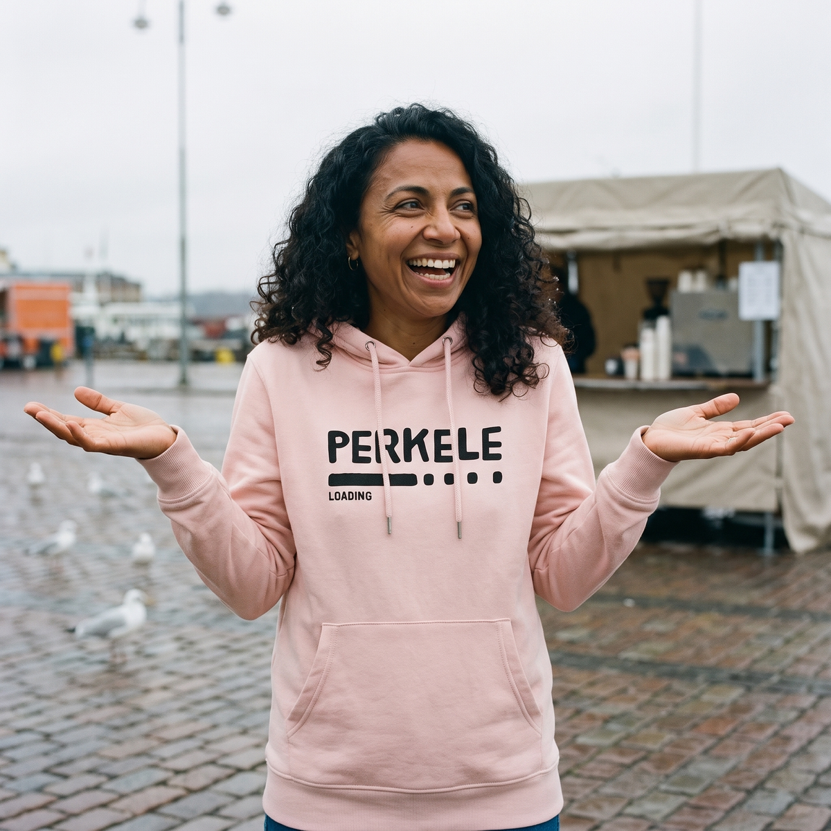 Perkele loading Finnish language hoodie in light pink, worn by Nea on a harbour market square, Very Finnish Problems