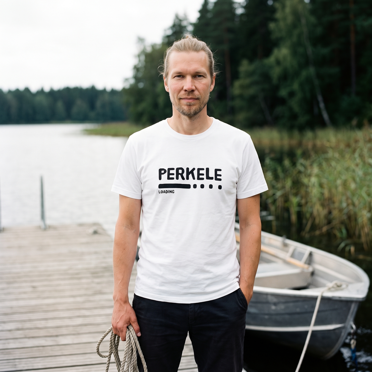 Perkele loading organic cotton t-shirt in white, worn by Joonas beside a lake rowing boat, Very Finnish Problems