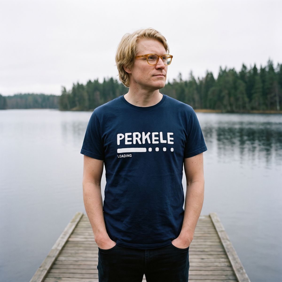 Perkele loading Finnish language t-shirt in navy, worn by Tuomas on a lake jetty, Very Finnish Problems