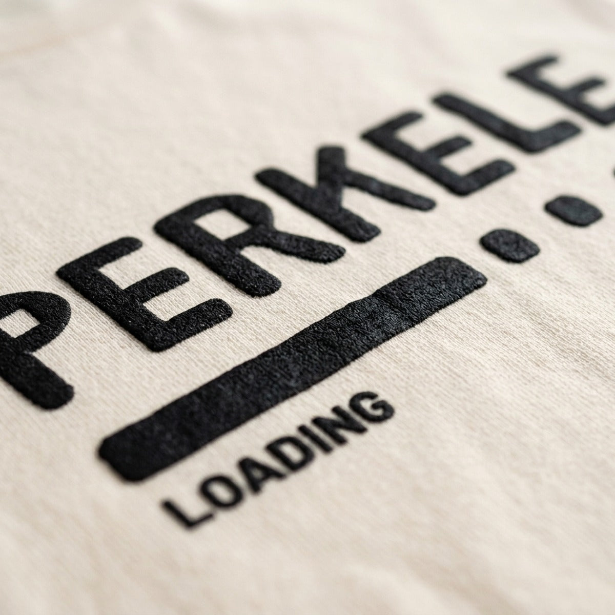 Close-up of the Perkele loading progress bar print on soft cream t-shirt fabric, Very Finnish Problems