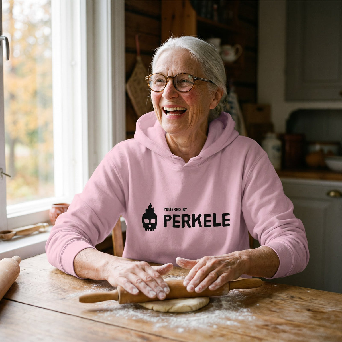 Powered by Perkele hoodie in light pink, worn by Raija baking pulla in a farmhouse kitchen, Very Finnish Problems
