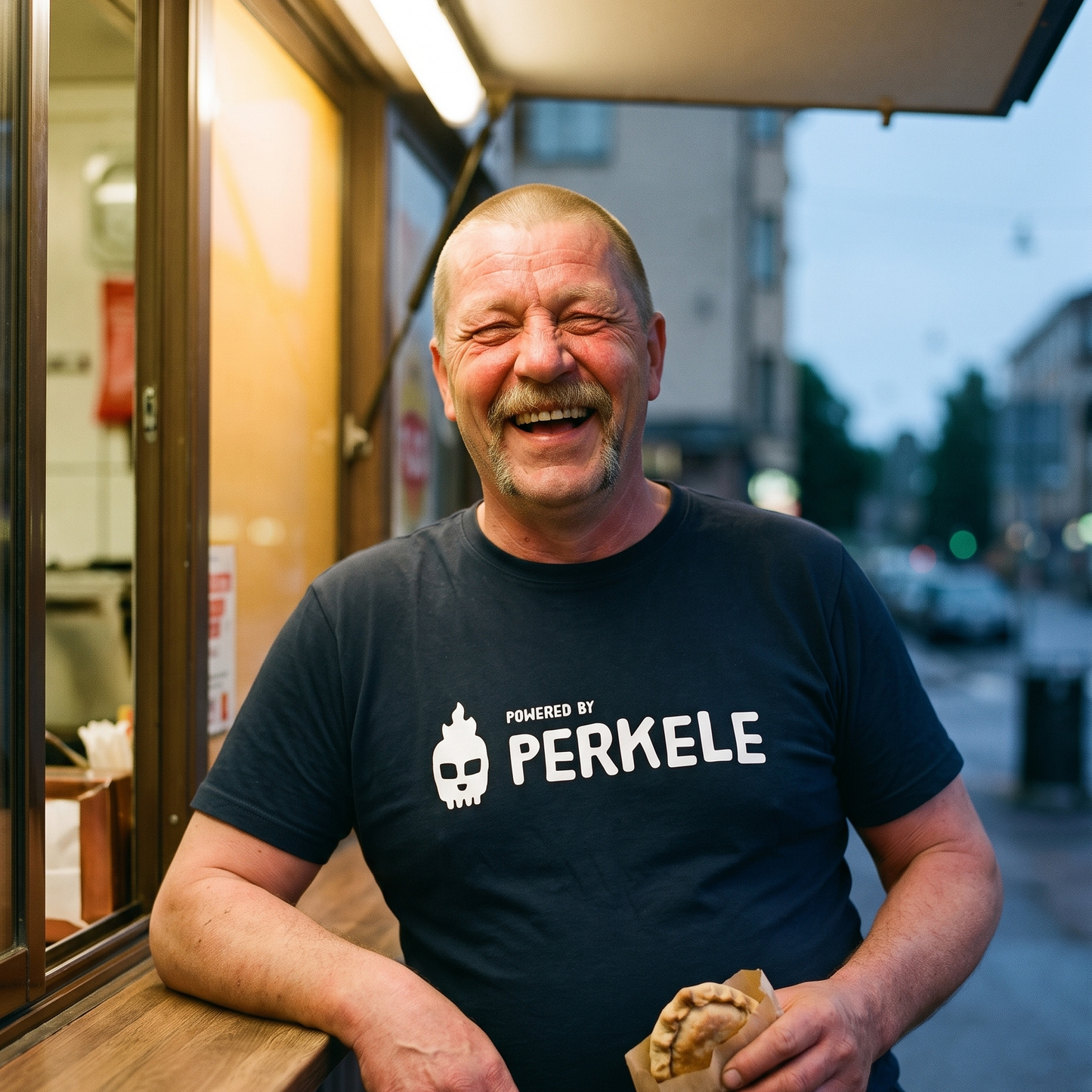 Powered by perkele t-shirt in navy, worn by Juha laughing at a Finnish grilli kiosk, Very Finnish Problems
