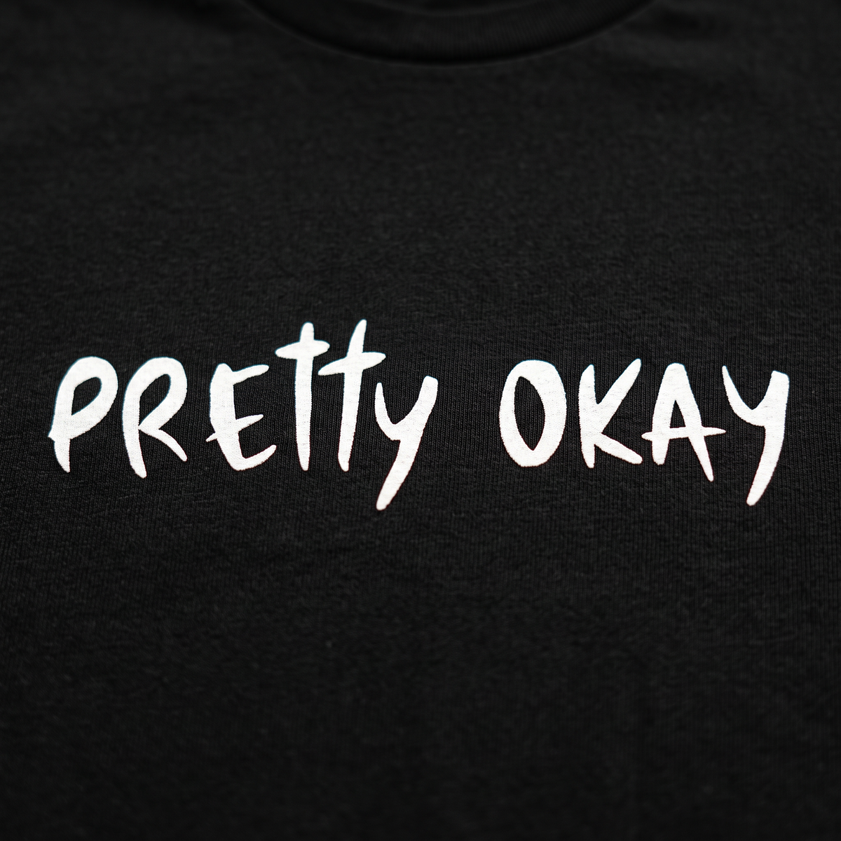 Close-up of the pretty okay print on black t-shirt fabric, Very Finnish Problems