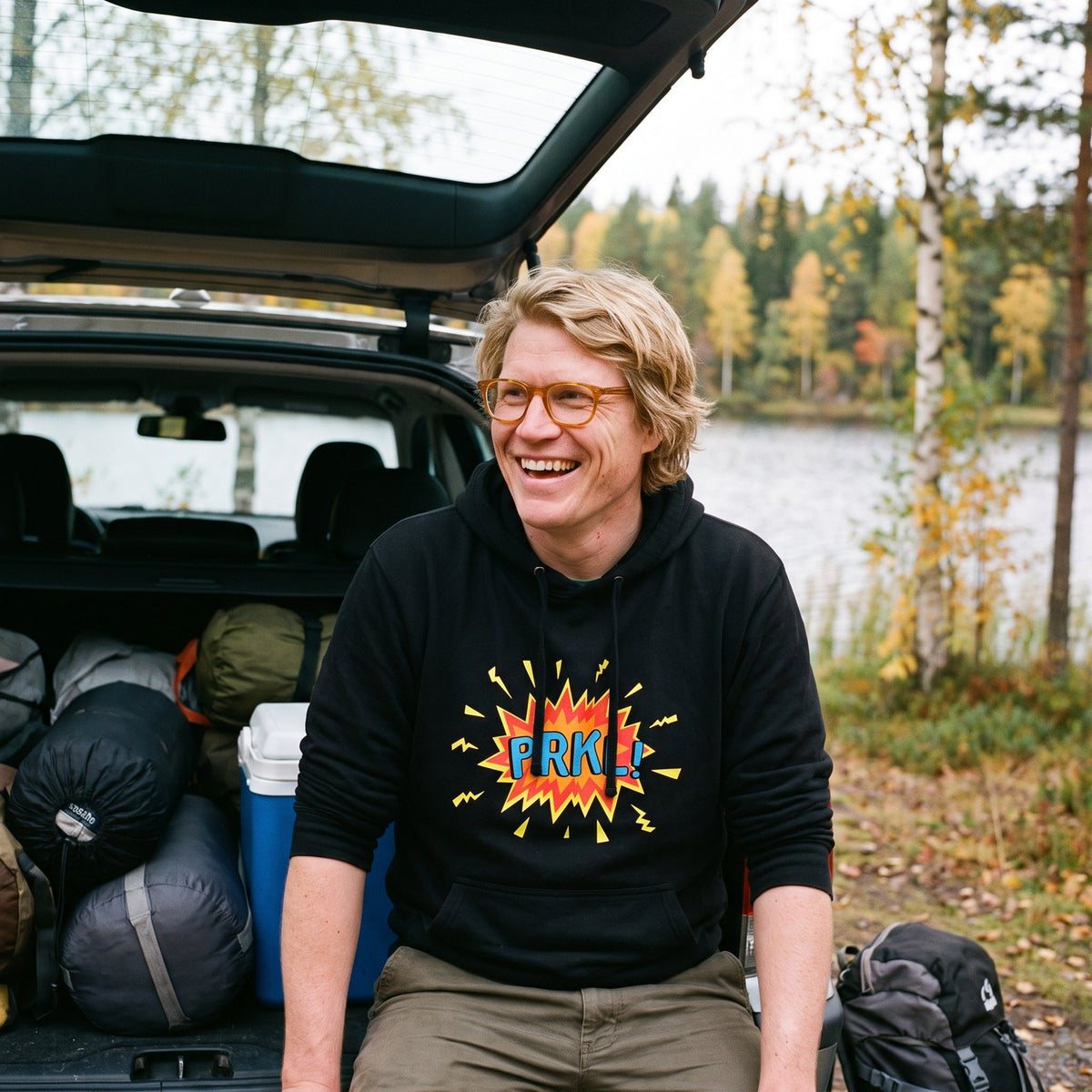 PRKL Bang hoodie in black, worn by Tuomas in an estate car by a lake, Very Finnish Problems