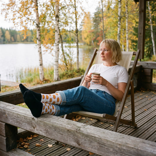 PRKL Bang socks, worn by Marika with her feet up on a cottage porch, Very Finnish Problems