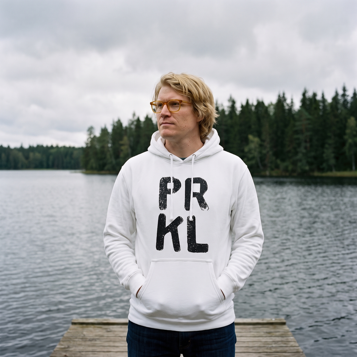 PRKL Finnish language hoodie in white, worn by Tuomas on a lake jetty, Very Finnish Problems