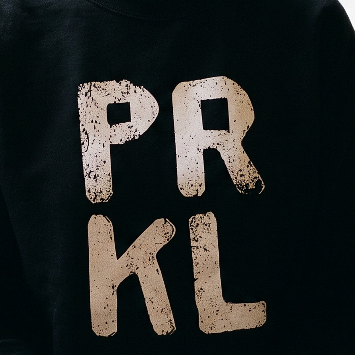 Close-up of the PRKL print on black sweatshirt fabric, Very Finnish Problems