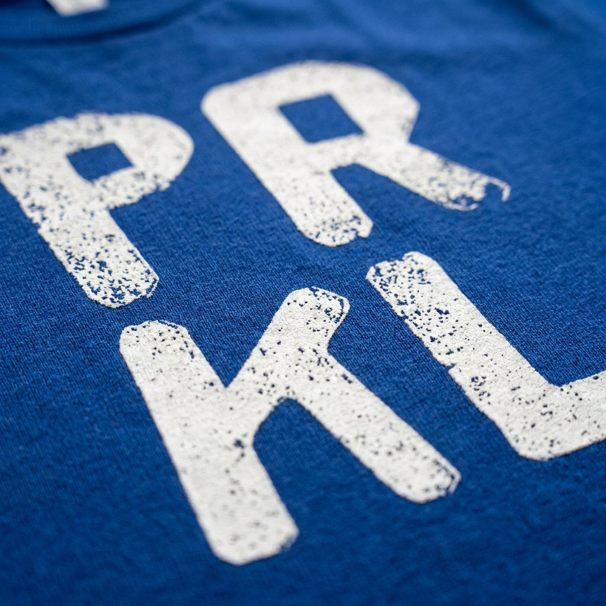 Close-up of the PRKL print on navy t-shirt fabric, Very Finnish Problems