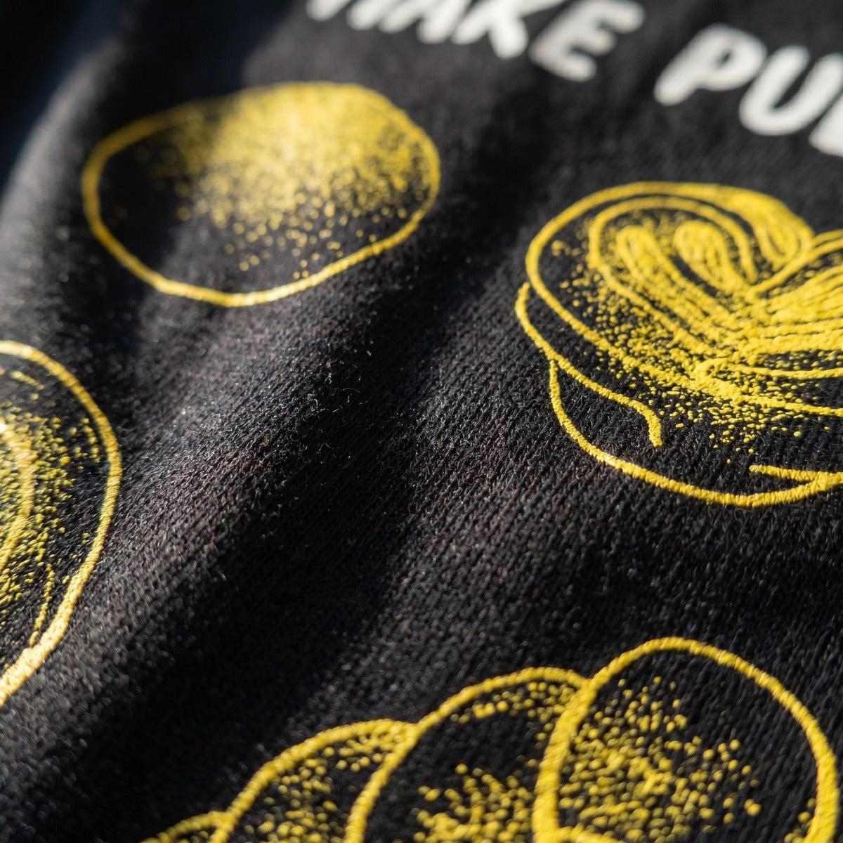 Close-up of the Make Pulla Not War bread illustration print on a t-shirt, Very Finnish Problems