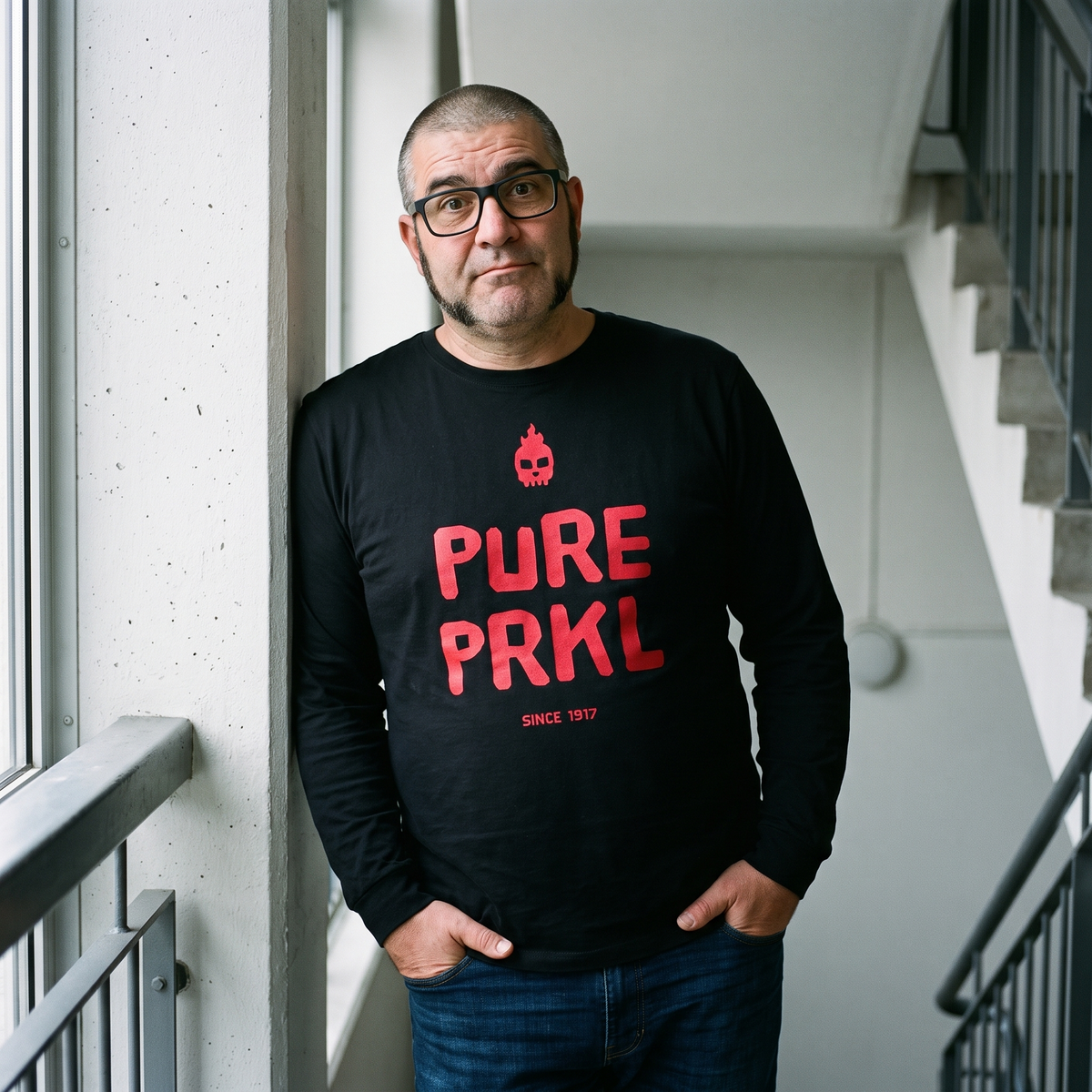 Pure PRKL long sleeve tee in black, worn by Jaska on a stairwell landing, Very Finnish Problems