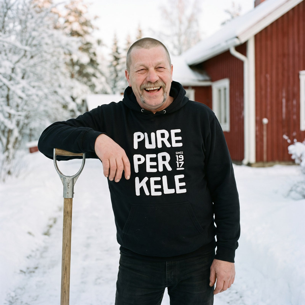 Pure Perkele since 1917 hoodie in black, worn by Juha shovelling snow at a cottage, Very Finnish Problems