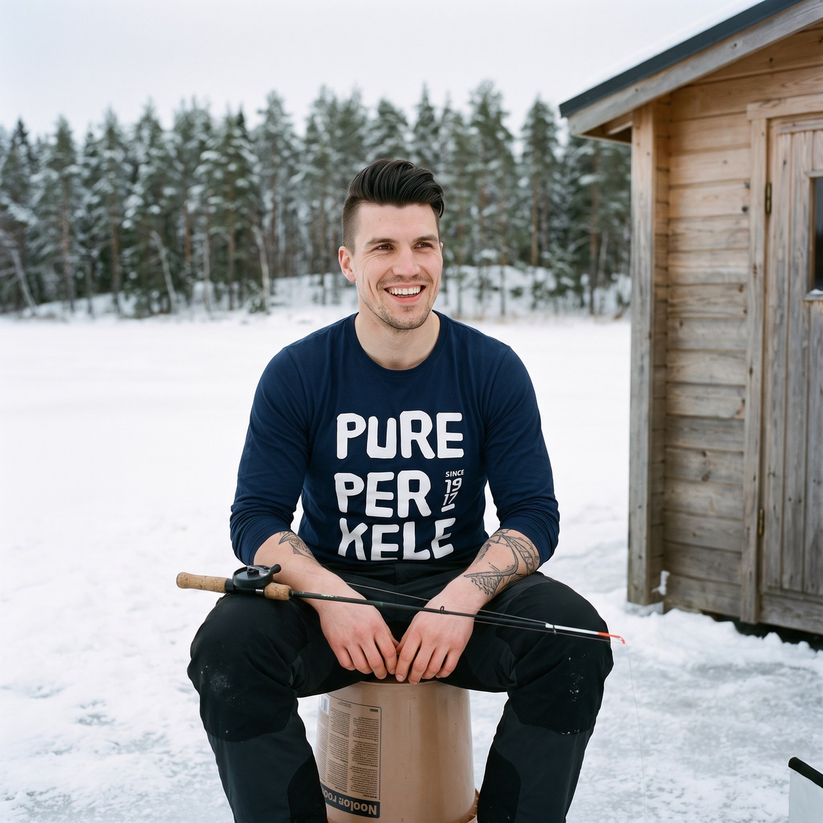 Pure Perkele Since 1917 long sleeve tee in navy, worn by Eetu beside an ice fishing hut on a frozen lake, Very Finnish Problems