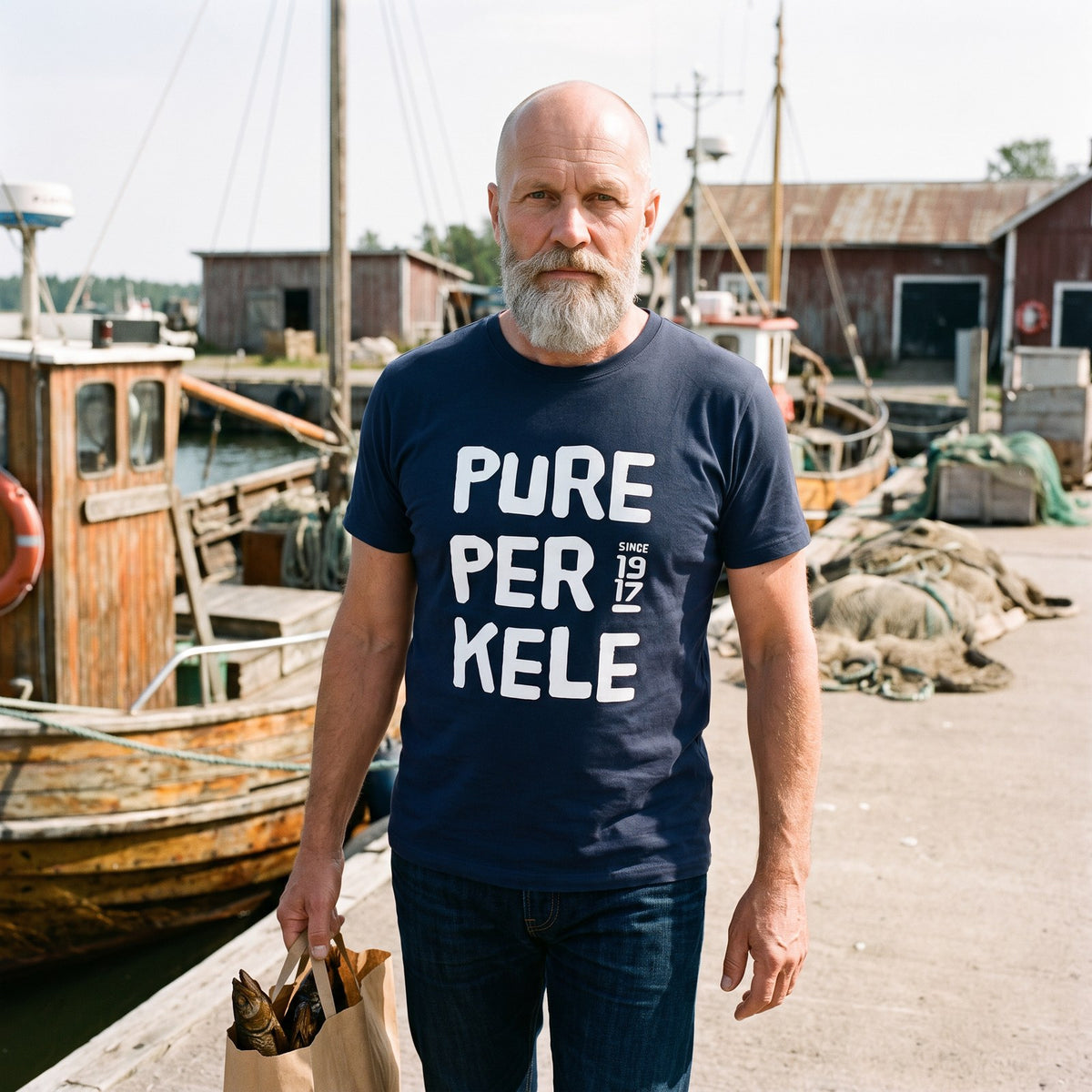 Pure Perkele since 1917 organic t-shirt in french navy, worn by Mikko on a harbour quay, Very Finnish Problems