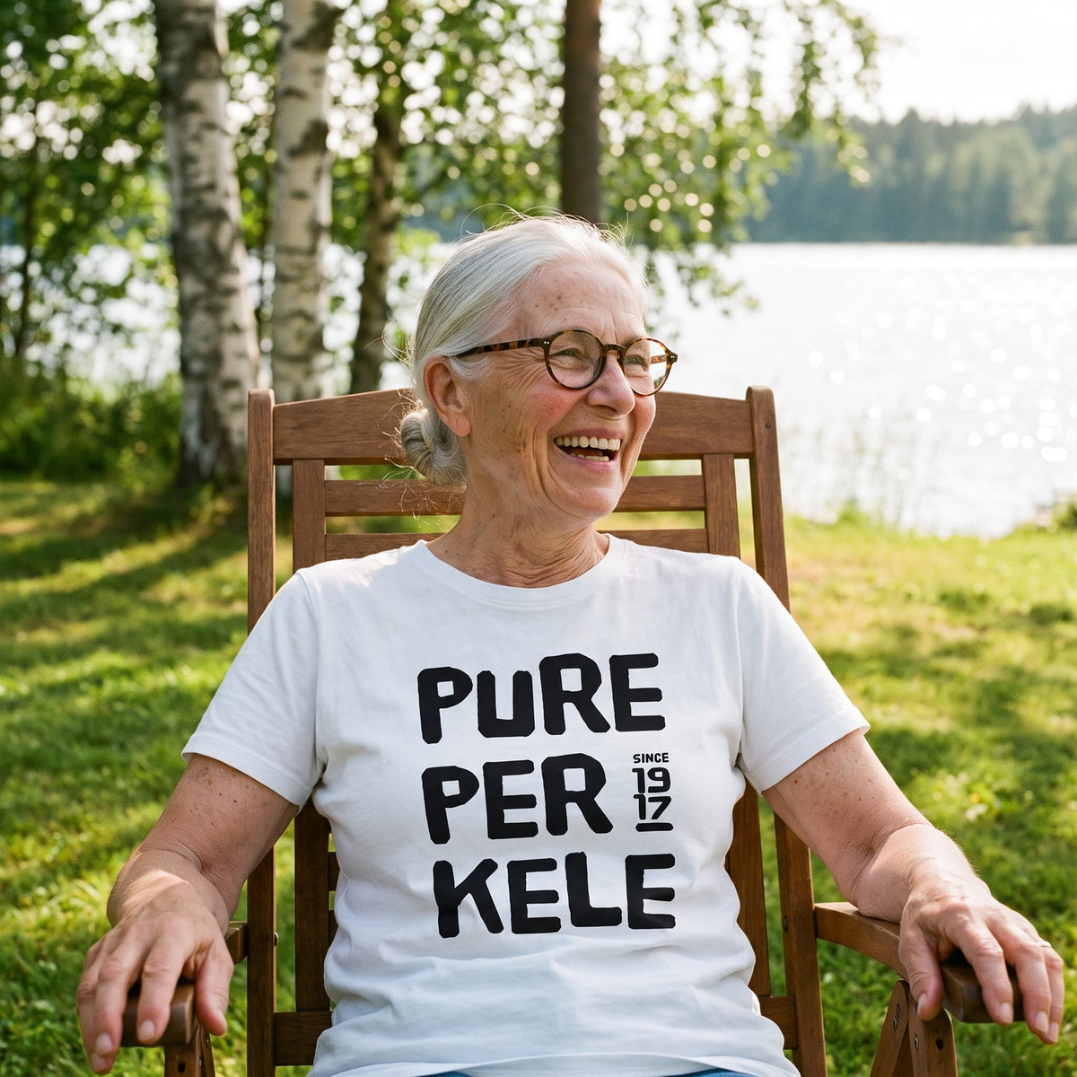Pure Perkele since 1917 organic t-shirt in white, worn by Raija in a cottage deckchair, Very Finnish Problems