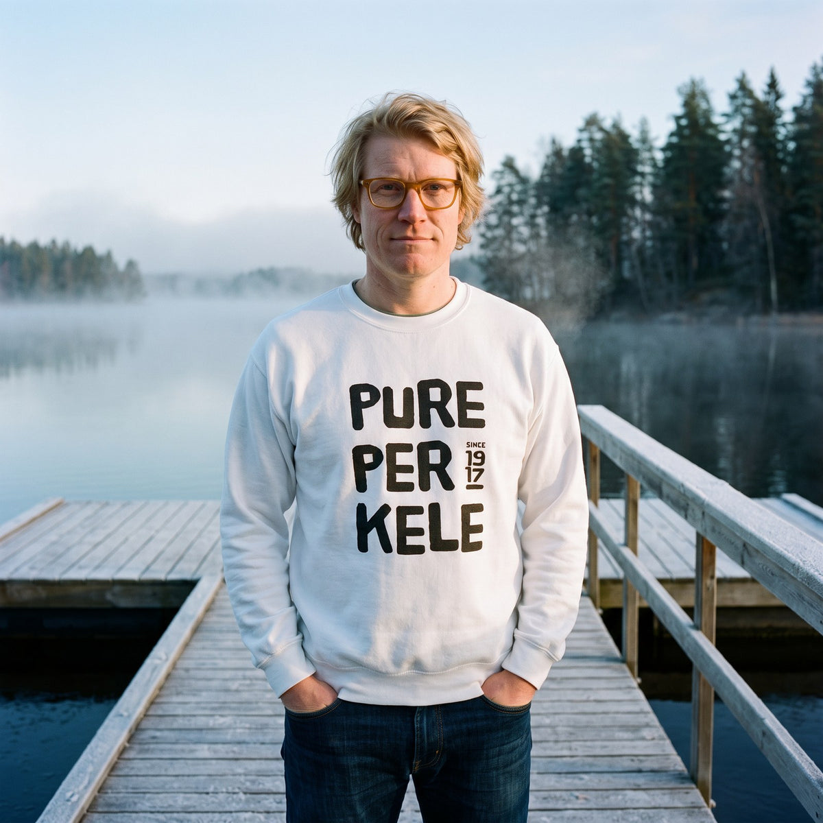 Pure Perkele since 1917 sweatshirt in white, worn by Tuomas on a frosty lake jetty, Very Finnish Problems