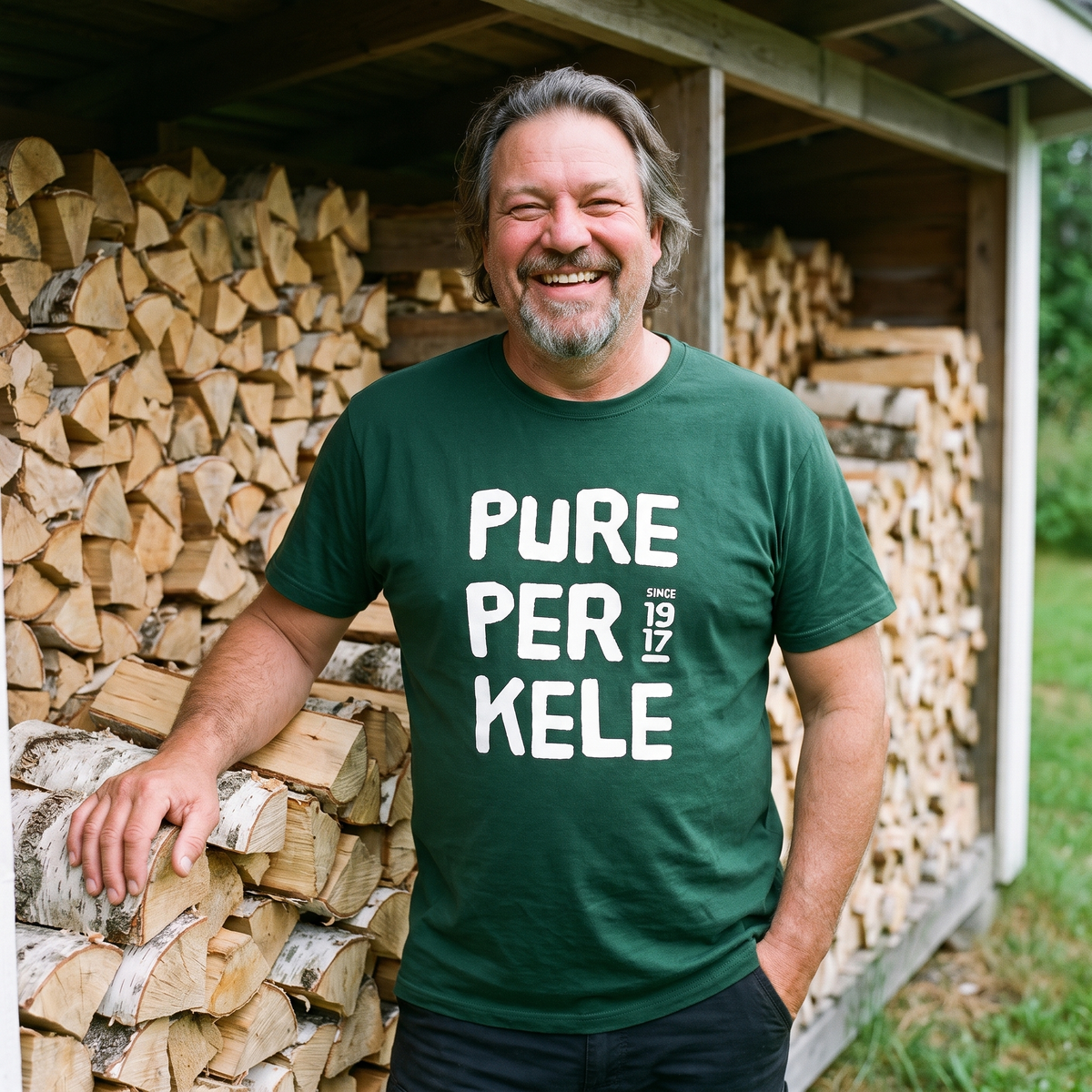 Pure Perkele since 1917 t-shirt in forest green, worn by Jojelli beside a woodpile, Very Finnish Problems
