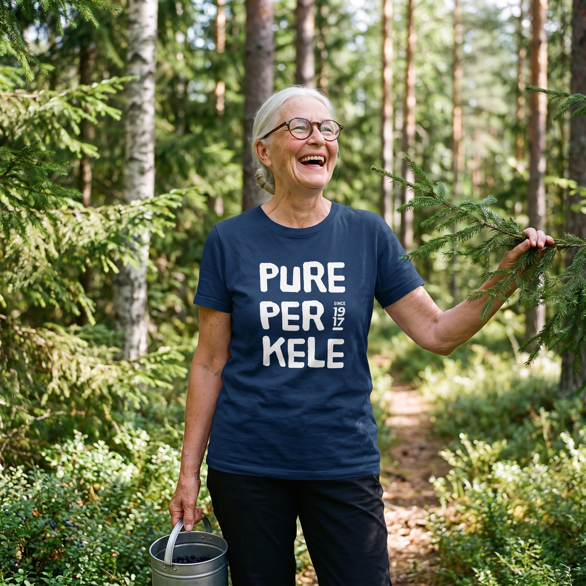 Pure Perkele since 1917 t-shirt in navy, worn by Raija on a forest path, Very Finnish Problems