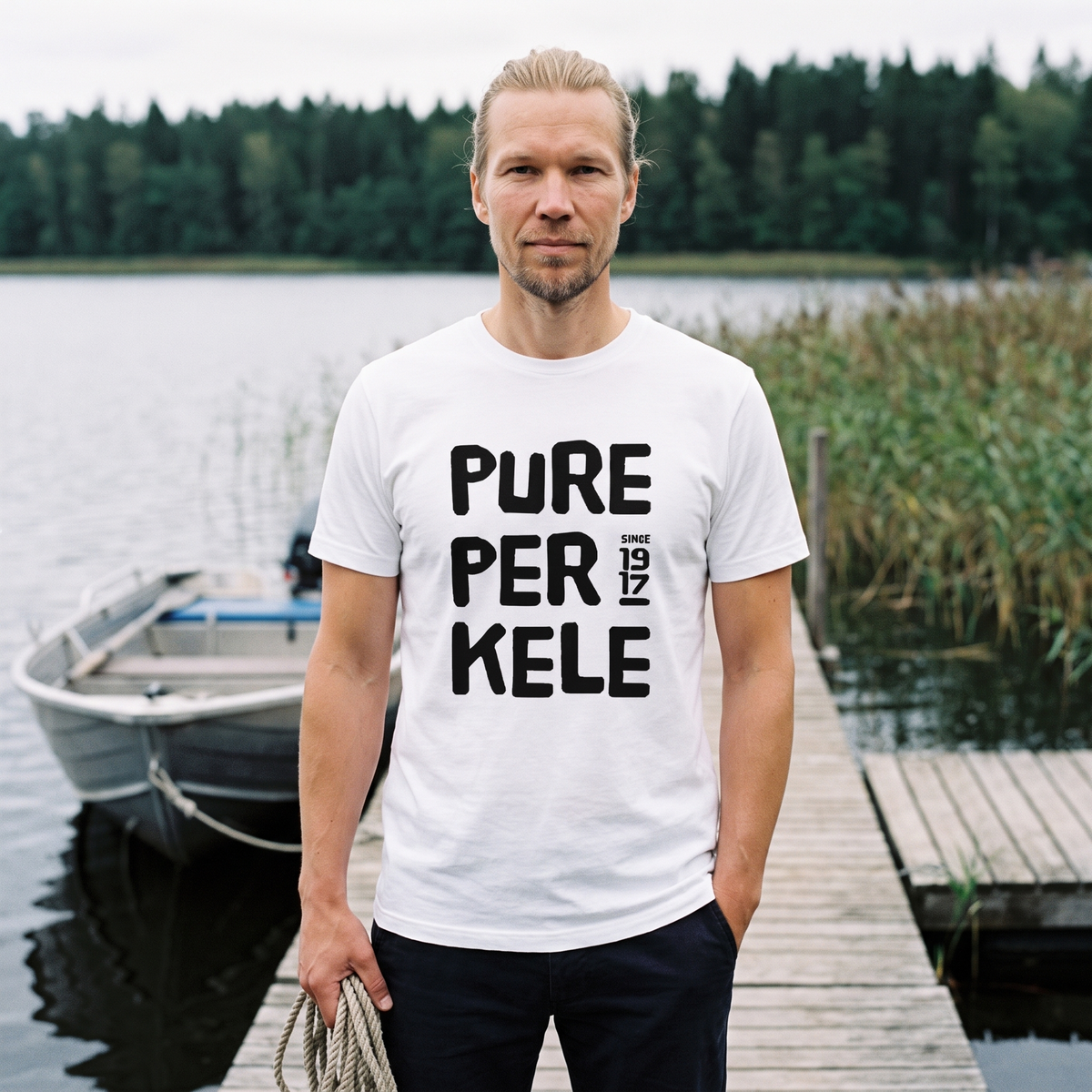 Pure Perkele since 1917 t-shirt in white, worn by Joonas on a lakeside jetty, Very Finnish Problems