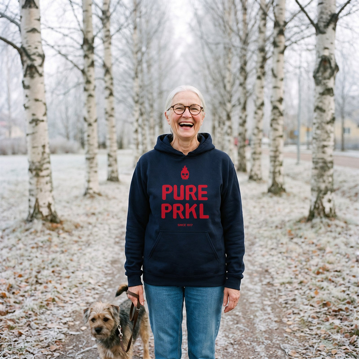 Pure PRKL hoodie in navy, worn by Raija walking a dog on a birch avenue, Very Finnish Problems