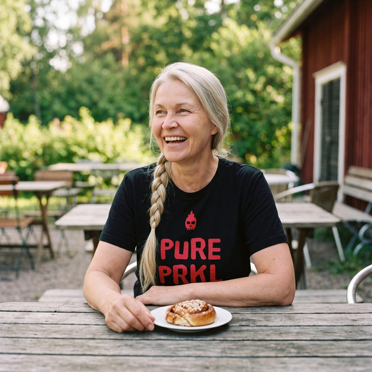 Pure PRKL organic t-shirt in black, worn by Anneli at a summer cafe, Very Finnish Problems