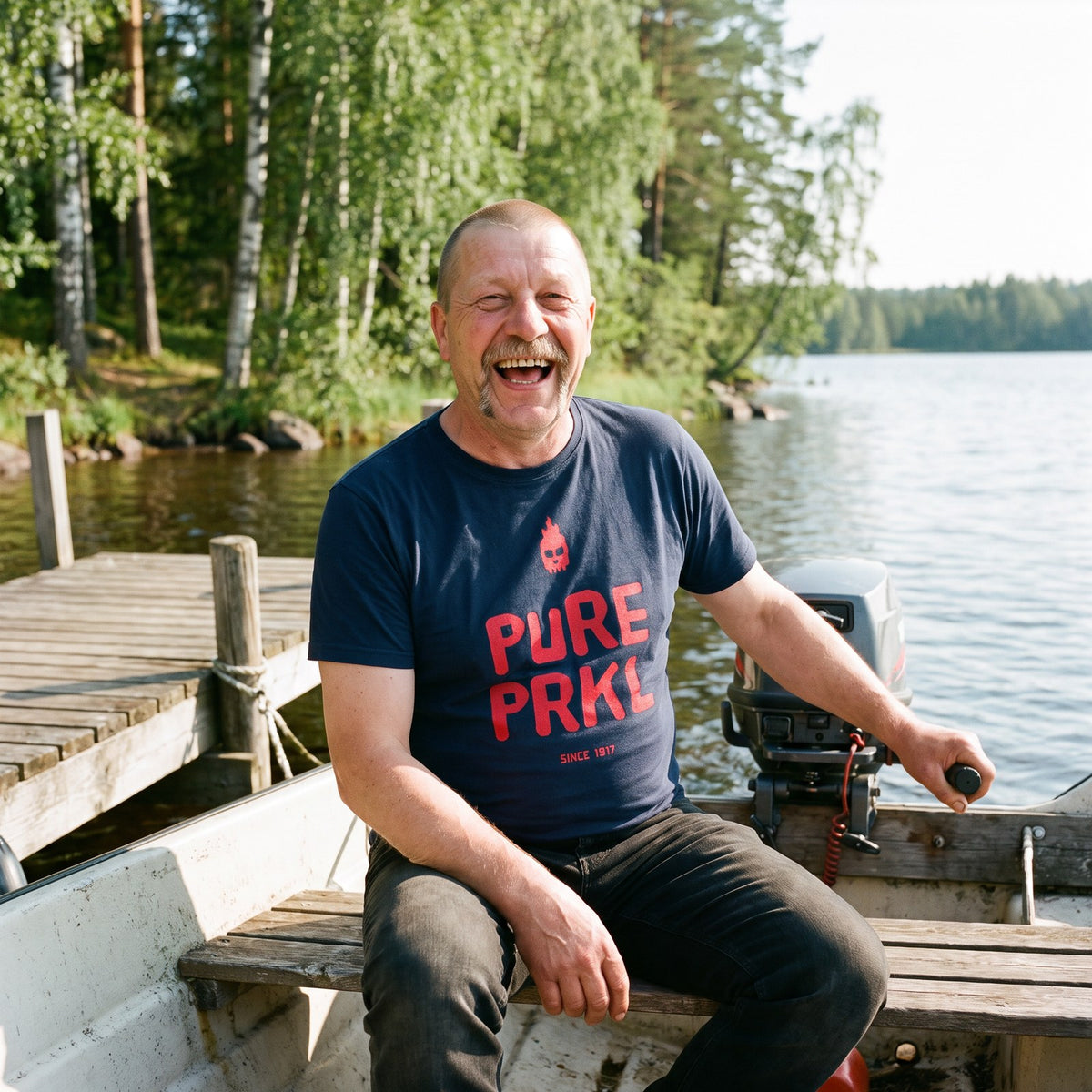 Pure PRKL organic t-shirt in french navy, worn by Juha in a moored motorboat, Very Finnish Problems